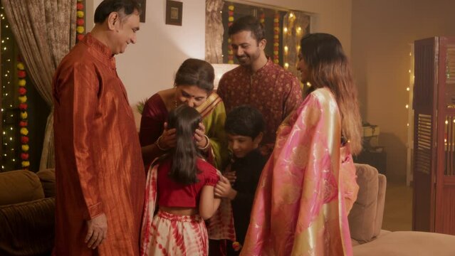 Happy smiling Hindu ethnic Indian family of Husband Wife and young kids taking blessings from their Elderly Parents on auspicious occasion of Diwali in a decorated home. Festival relationship concept