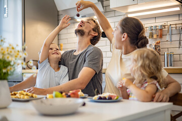 Happy family enjoying weekend breakfast together sitting at table in kitchen dessert waffles
