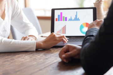 Two businessmen talking in a board room about joint business and summarize the company's profits with a graph showing successful performance. A colleague reviewed the results of the quarterly report.