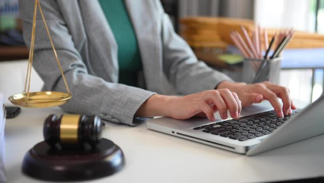 Justice and law concept.Male judge in a courtroom with the gavel, working with, computer and  docking keyboard, eyeglasses, on table in morning light.