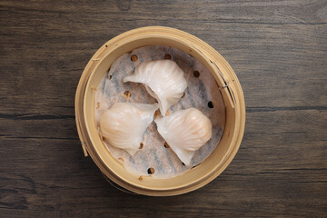 crystal har gow transparent prawn shrimp chicken meat stuffed dim sum in bamboo steamer chopsticks chili soya sauce on wooden table