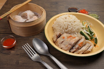 steamed Hainanese chicken rice crystal har gow transparent prawn shrimp meat stuffed dim sum in bamboo steamer green red chilli ginger soya sauce cucumber carrot on retro enamel diner plate fork spoon
