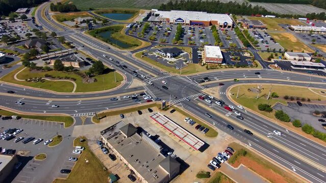 aerial footage of the city of Warner Robins Georgia with restaurants, offices buildings,  warehouses and a water park surrounded by vast miles of lush green trees with a gorgeous clear blue sky