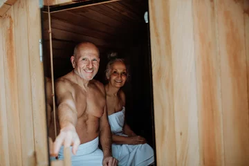Gartenposter Senior couple enjoying together time in wooden sauna, relax, spa and healthy lifestlye concept. © Halfpoint