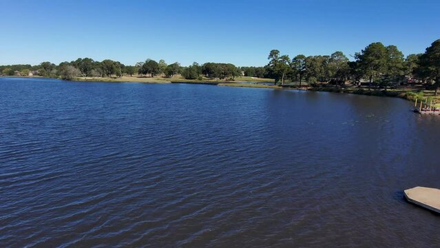 aerial footage of a gorgeous autumn landscape at Houston Lake with rippling blue water surrounded by lush green trees, grass and plants with a golf course and homes along the banks in Warner Robins