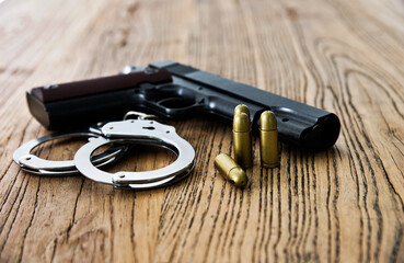 Handcuffs and gun on wooden table