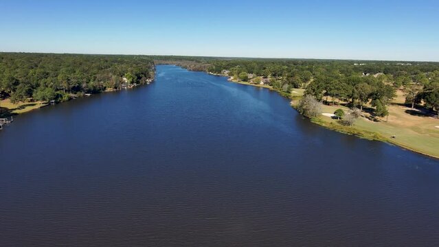 aerial footage of a gorgeous autumn landscape at Houston Lake with rippling blue water surrounded by lush green trees, grass and plants with a golf course and homes along the banks in Warner Robins