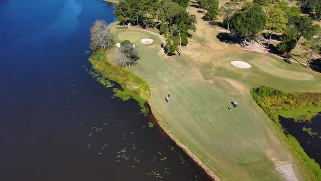aerial footage of a gorgeous autumn landscape at Houston Lake with rippling blue water surrounded by lush green trees, grass and plants with a golf course and homes along the banks in Warner Robins