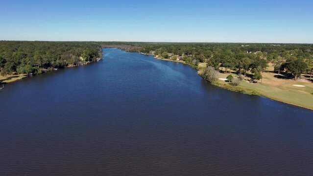 aerial footage of a gorgeous autumn landscape at Houston Lake with rippling blue water surrounded by lush green trees, grass and plants with a golf course and homes along the banks in Warner Robins