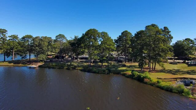 aerial footage of a gorgeous autumn landscape at Houston Lake with rippling blue water surrounded by lush green trees, grass and plants with a golf course and homes along the banks in Warner Robins