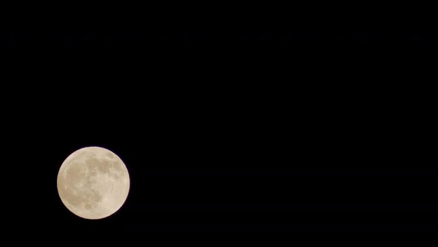 Yellow full moon at black sky and clouds background at night. Astronomical body orbits planet Earth. Permanent natural satellite. Timelapse footage