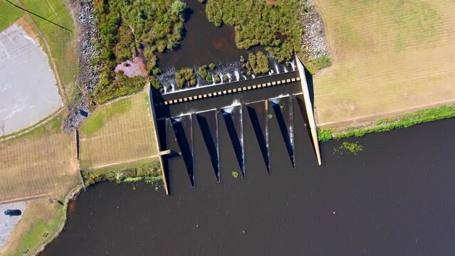 aerial footage of a gorgeous summer landscape on the lake with a water fall surrounded by lush green trees, grass and plants at Houston Lake in Perry Georgia USA