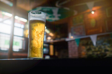 Pint glass of lager beer of cider on a table in bar in focus. Selective focus. Cinematic tone....