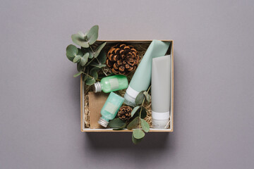 Beauty box with face and body care products on  grey background. Tubes with cream and lotion, soap, eucalyptus leaves. Organic cosmetics gift