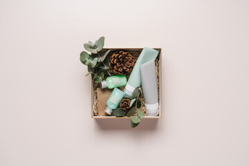 Beauty box with face and body care products on  light background. Tubes with cream and lotion, soap, eucalyptus leaves. Organic cosmetics gift