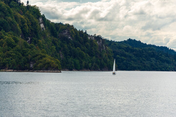 A lonely sailboat on a lake surrounded by mountain rocks. Czorsztyn, Poland