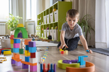 Confident male kid building fortress tower architecture wooden bricks ecology Montessori material