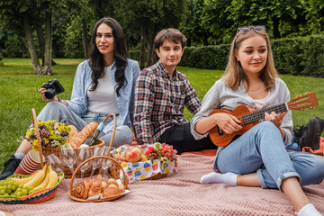 Shot of two men and two women friends spending time together at picnic at nature.