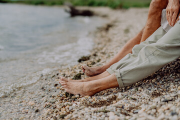Close up seniors legs at beach near sea, resting together.