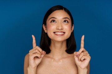 Young beautiful smiling happy asian woman looking and pointing upward