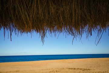Fototapeta na wymiar sombrilla de brezo y madera en un playa (viajar, vacaciones)