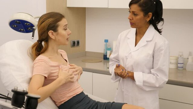 Experienced plastic surgeon consulting woman about breast augmentation at clinic. High quality 4k footage