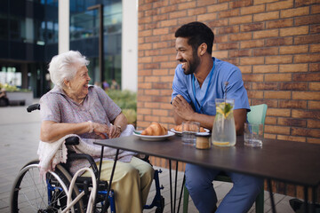 Fototapeta premium Caregiver having breakfast with his client at cafe.