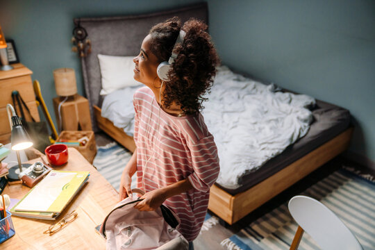 Black Girl Listening Music While Packing Her Backpack In Bedroom