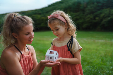 Little girl with her dad holding paper model of house with solar panels.Alternative energy, saving...