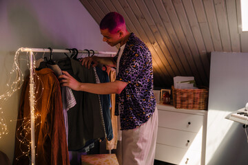 Young handsome stylish boy choosing clothes on wardrobe rail