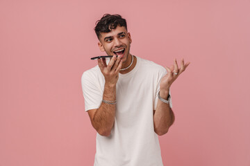 Young stylish man with raised hand talking phone on speakerphone