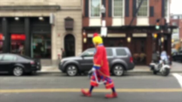Blurred shot of people dressed up as clowns walking in the street, slow motion.