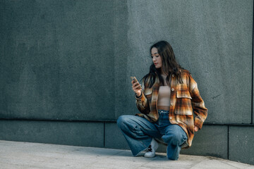 urban girl using the phone or smart phone with wall background