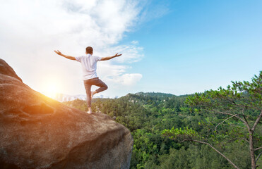Young man doing yoga on mountain peak