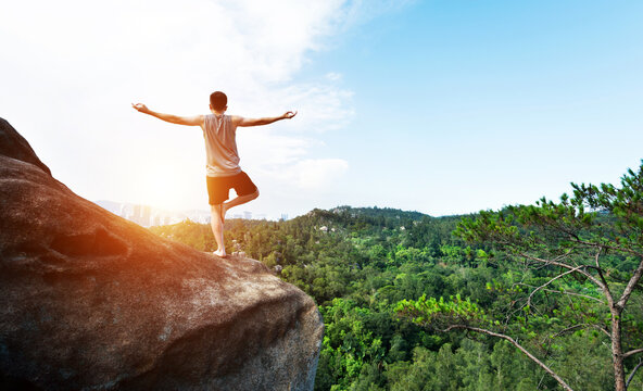 Young man doing yoga on mountain peak