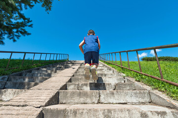 Rear view of young boy climbs up on staircase