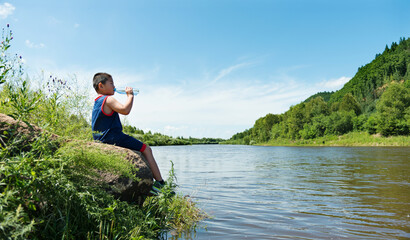 Naklejka premium Little asian boy drinking water by the lake