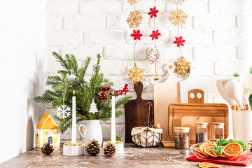 Beautiful interior part of the modern kitchen decorated for the New Year and Christmas. spruce bouquet, cones, handmade garland on a white brick wall.