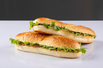 Yummy baguette sandwich with various vegetables and slices of cheese placed on white background in studio