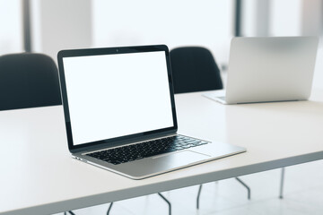 Fototapeta premium Close up of empty white laptop on white desktop, mock up place on screen, blurry office interior background. 3D Rendering.
