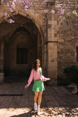 Fototapeta na wymiar In full length, pretty young caucaisan woman posing near old european castle in sunny weather. Brunette wears casual style of clothes. Concept leisure vacation.