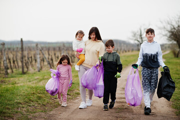 Fototapeta premium Family with trash bag collecting garbage while cleaning in the vineyards . Environmental conservation and ecology, recycling.