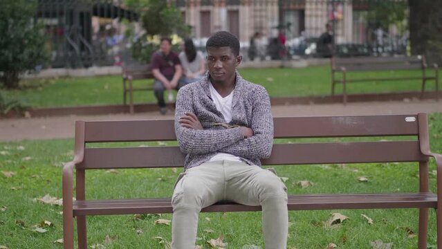 Handsome black man sitting on the bench and looking pensive