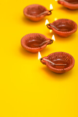 Concept of indian festival diwali. Traditional oil lamps on yellow background.