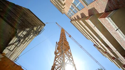 construction crane bottom view. Construction of a house. The sun's rays shine through a construction crane.