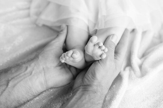 Baby feet in father hands. Tiny newborn baby's feet on male hands closeup. Dad and his child. Happy Family concept. Beautiful conceptual image of parenthood