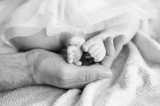 Baby feet in father hands. Tiny newborn baby's feet on male hands closeup. Dad and his child. Happy Family concept. Beautiful conceptual image of parenthood