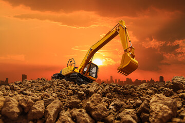 Excavator is digging in the construction site  on a sunset background . © chaphot