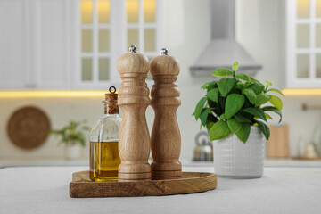 Wooden salt and pepper shakers, bottle of oil on white table in kitchen
