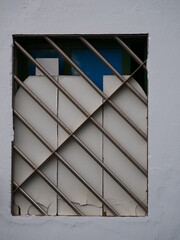 Broken window which has been secured by metal bars and wooden slats